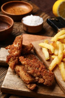 Tahta arka planda patates kızartması ve kızarmış morina balığı tahtaları.