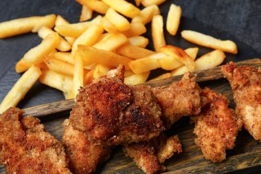 Koyu arka planda ahşap tahtada kızarmış morina balığı, yakın plan.