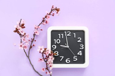 Çiçekli bahar dalları ve leylak arkaplan üzerindeki saat