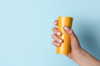 Mavi arka planda çöp torbası rulosu tutan kadın.