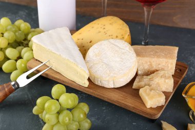 Masanın üzerinde değişik peynir ve üzümler olan tahta tahta tahta bir masa.