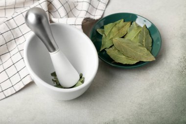 Açık arkaplanda defne yaprakları olan havan topu ve tokmak