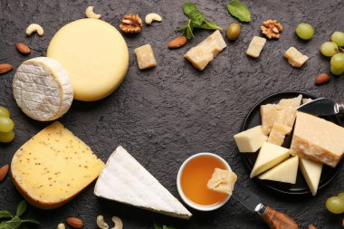 Lezzetli peynirden yapılmış çerçeve, fındık, üzüm ve bal siyah arka planda