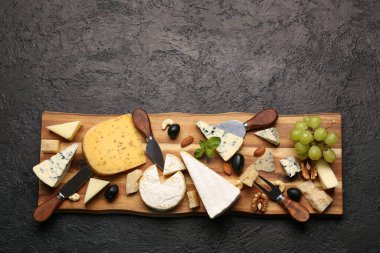 Koyu arka planda farklı çeşit lezzetli peynirli ahşap tahta.