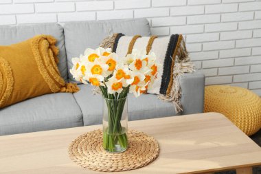 Aydınlık oturma odasındaki masada çiçek açan vazo.