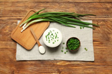 Ahşap arka planda yeşil soğanlı lezzetli ekşi krema kaseleri