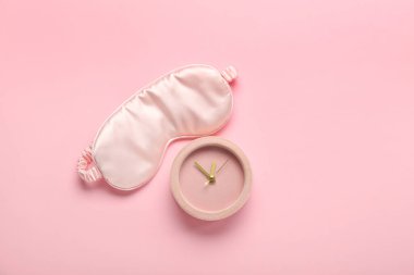 Uyku maskesi ve pembe bir arka plan üzerinde çalar saat