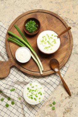 Ekşi kremalı kompozisyon ve grunge masasında yeşil soğan.