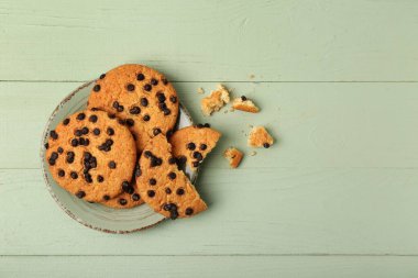 Yeşil ahşap arka planda çikolata parçalı lezzetli kurabiyeler.