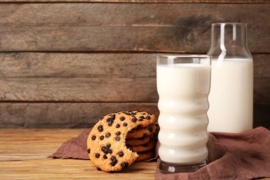 Çikolata parçalı lezzetli kurabiyeler ve ahşap arka planda bir bardak süt.