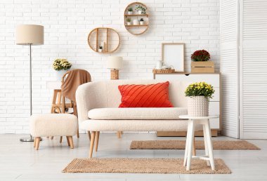 Beyaz kanepe ve kahve masasında kasımpatı çiçekleri olan şık bir oturma odası.