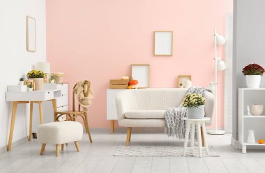 Beyaz kanepe ve kahve masasında kasımpatı çiçekleri olan şık bir oturma odası.