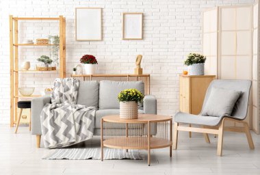 Kahve masasında gri kanepe ve kasımpatı çiçekleri olan modern bir oda.