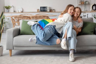 Evdeki kanepede sarılan genç lezbiyen çift.