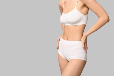 Gri arka planda iç çamaşırlı genç bir kadın. Epilasyon kavramı