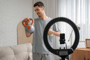 Dambıl ve kettlebell kayıt videolu neşeli erkek blogcu