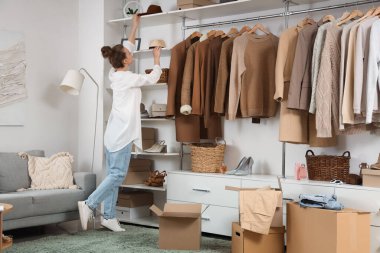 Soyunma odasında şık aksesuarlar düzenleyen elbise kutularıyla güzel genç bir kadın.