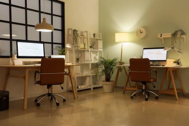 Modern bilgisayarları ve parlak lambaları olan programcıların şık işyerleri