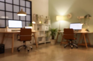 Modern bilgisayarları ve parlak lambaları olan programcıların şık işyerleri, bulanık görünüm