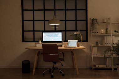 Programcının işyeri, modern bilgisayar ve gece ofiste parlayan lambalar.