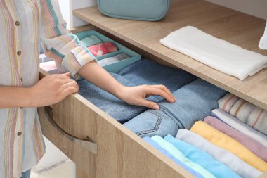 Kadın çekmecelerden elbise alıyor. Yakın çekim.