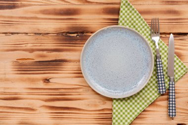 Tabak, çatal bıçak ve peçeteyle ahşap zemin.