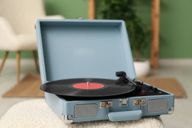 Odadaki sehpanın üzerinde diski olan bir plak çalar.