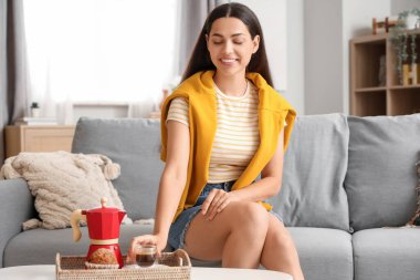 Elinde bir fincan sıcak espresso, gayzer kahve makinesi ve evde kek yapan güzel bir kadın.