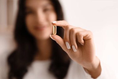 Beautiful young happy woman with healthy fish oil capsule at home