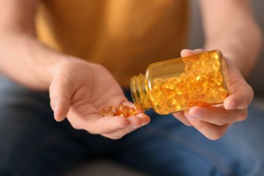 Evde balık yağı kapsülü dolu kavanozu olan yakışıklı genç adam.