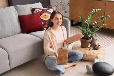 Sadhu tahtası olan genç bir kadın evdeki halıda oturuyor.