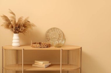 Bej duvarın yanında farklı dekorları olan ahşap raf ünitesi.