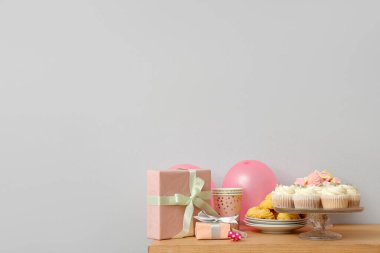 Beyaz duvara karşı doğum günü partisi için farklı şekerlemeler, hediyeler ve balonlar.