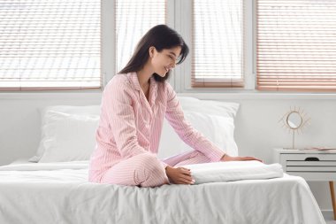 Yatakta yumuşak ortopedik yastıklı pijamalı genç bir kadın.