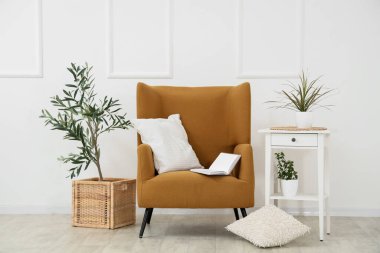 Kahverengi koltuklu, yastıklı, sehpalı ve çiçekli bir oturma odası.