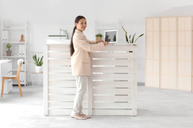 Modern dizüstü bilgisayarla çalışan genç bayan resepsiyonist.