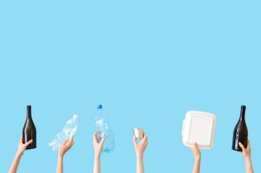 Mavi arka planda farklı çöpleri tutan kadın eller. Geri dönüşüm kavramı