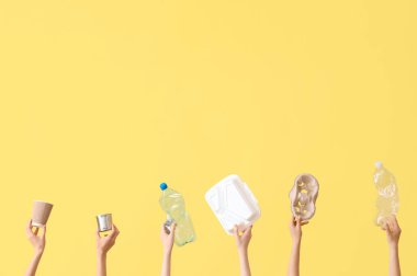 Sarı arka planda farklı çöpleri tutan kadın elleri. Geri dönüşüm kavramı