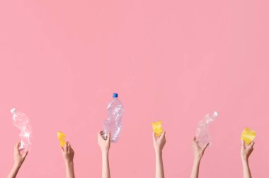 Pembe arka planda plastik çöpleri tutan kadın eller. Geri dönüşüm kavramı