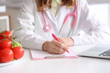 Mutfaktaki masada panoya yazı yazan kadın beslenme uzmanı.