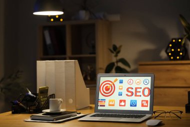 Laptop ve kısaltma SEO karanlık ofiste masanın üstünde.