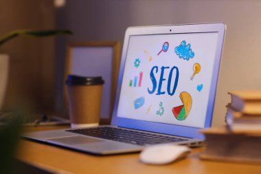 Laptop ve kısaltma SEO karanlık ofiste, masada, yakın plan.