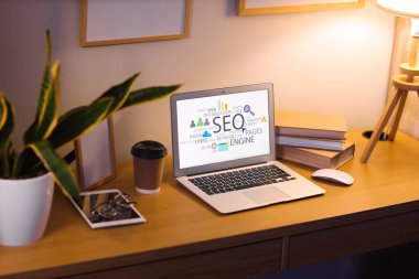 Laptop ve kısaltma SEO rahat karanlık ofiste masada.
