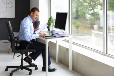 Ofiste hesap makinesiyle çalışan erkek muhasebeci.