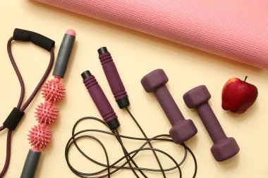 Elma ve bej arka planda farklı spor ekipmanları