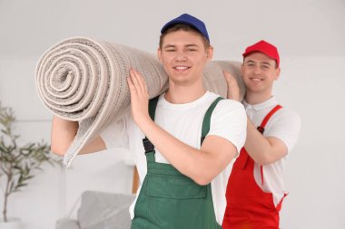 Yükleyiciler şık bir odada halı taşıyor.