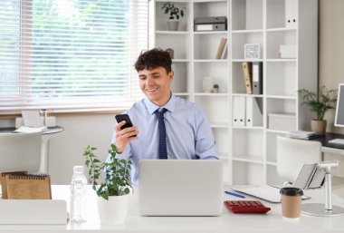 İş yerinde çalışan cep telefonu ve modern bilgisayarlı bir erkek muhasebeci.