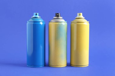 Mavi arka planda sprey boya kutuları