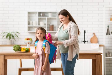 Anne ve kızı mutfakta okula gitmek için sırt çantalarını hazırlıyorlar.