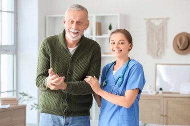 Evde gülümseyen hemşire yüzünden Parkinson sendromu geçiren yaşlı bir adam.